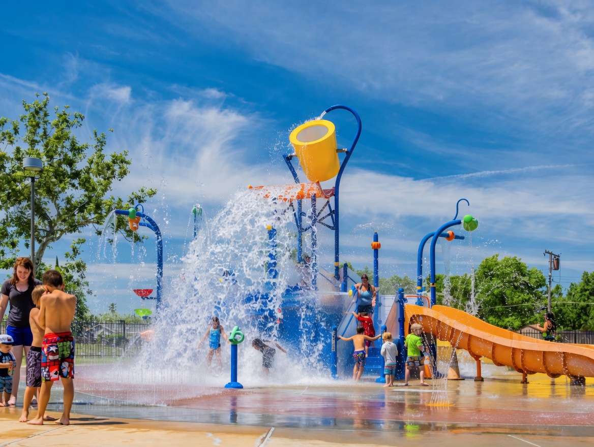 White Rock–style splash park with yellow dump bucket, water jets, orange slide