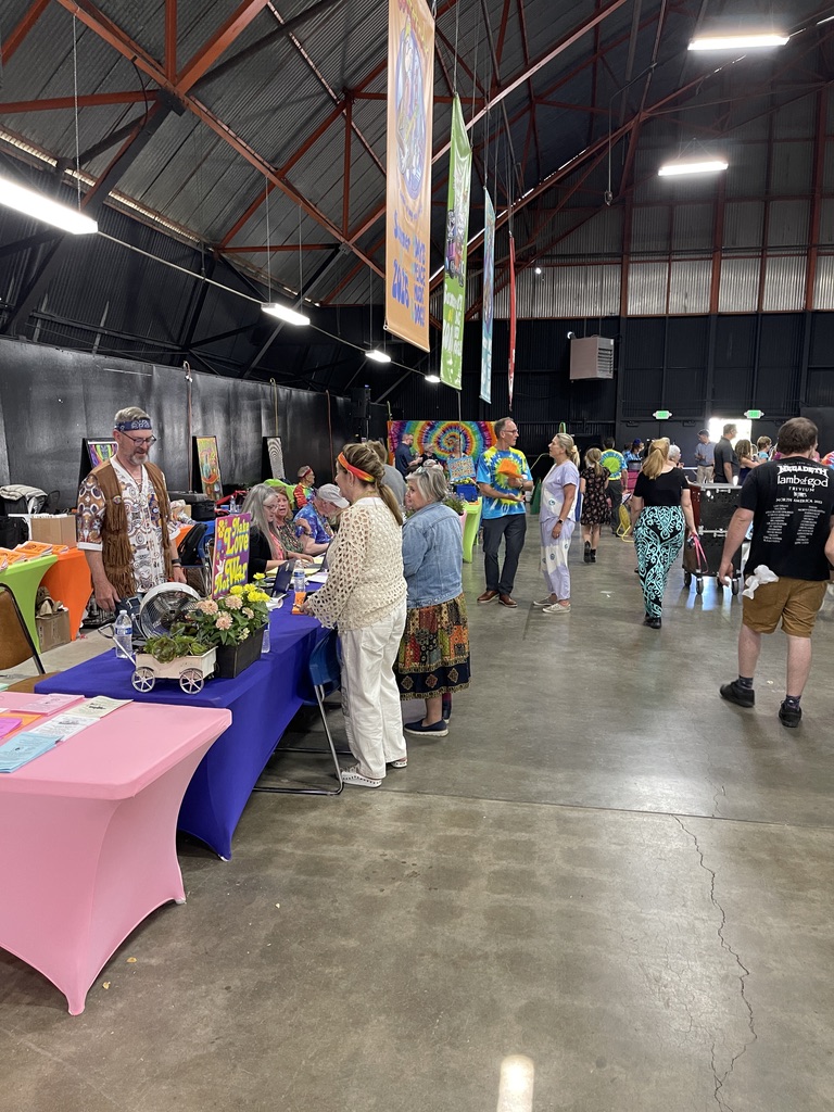 People lined up at indoor vendor and check-in tables with colorful banners